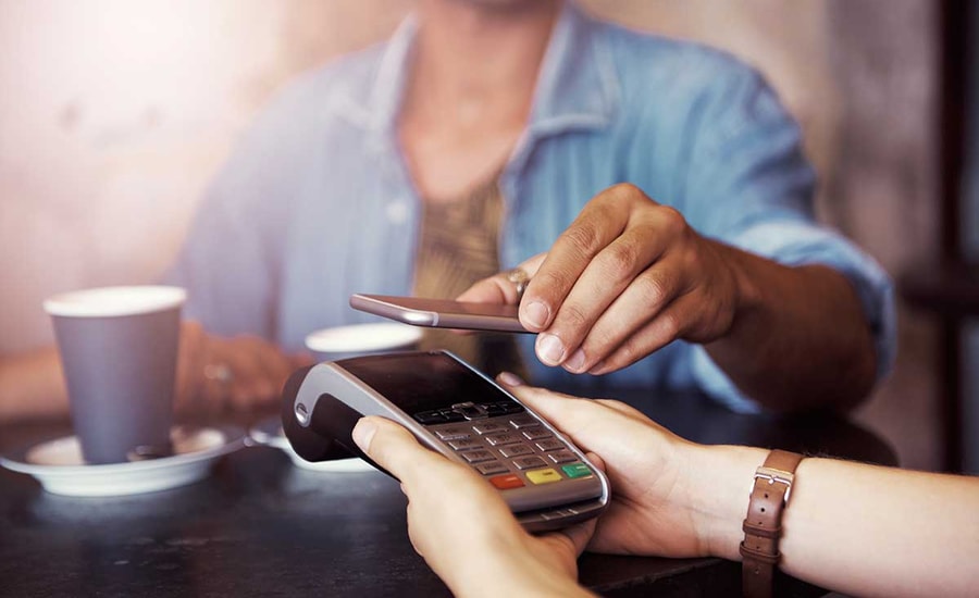 Kvinne på kafé betaler med Google Pay på mobilen