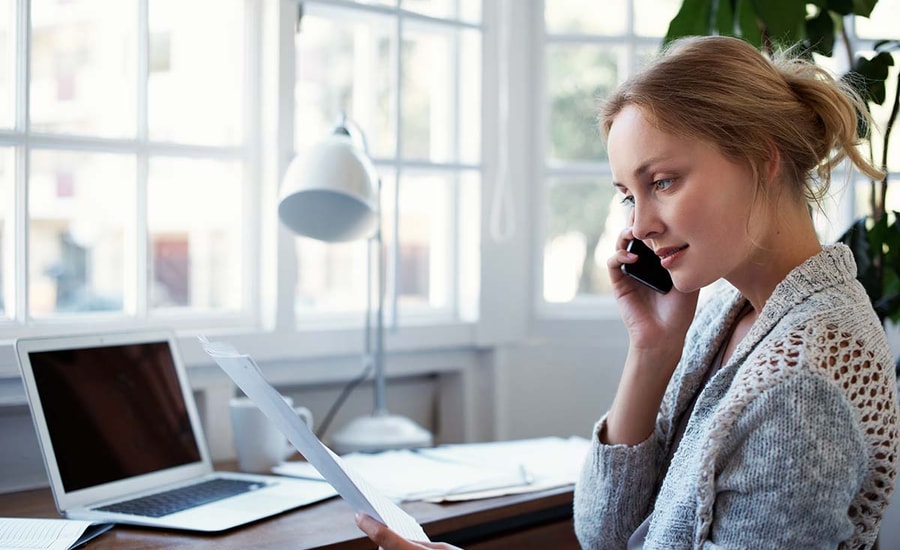 Kvinne snakker i telefonen mens hun holder et dokument, til illustrasjon for gjeldsordning