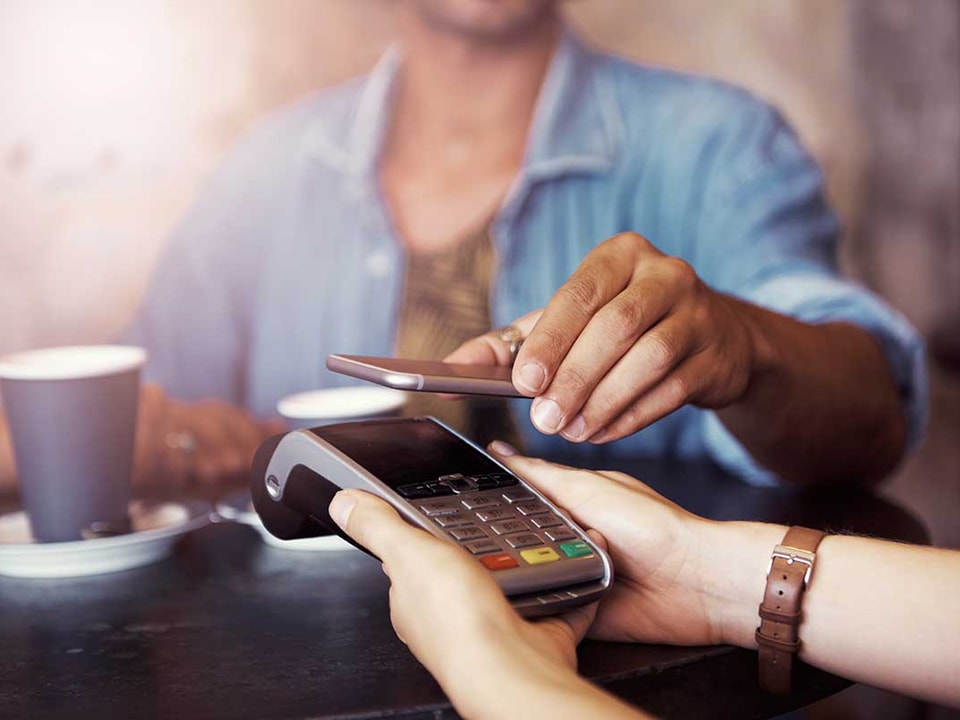 Kvinne på kafé betaler med Google Pay på mobilen