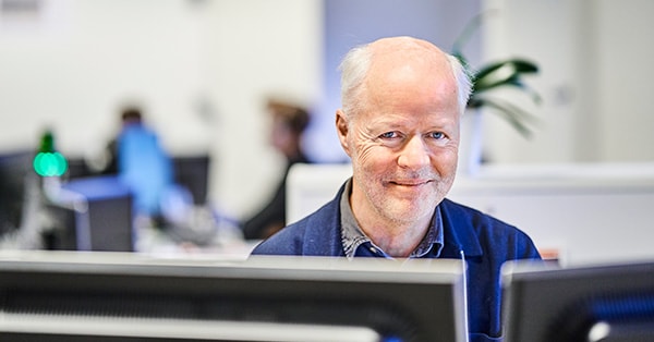 Terje som er kundekonsulent for SeniorLån i BN Bank sitter i lokalet fremfor to PC-skjermer
