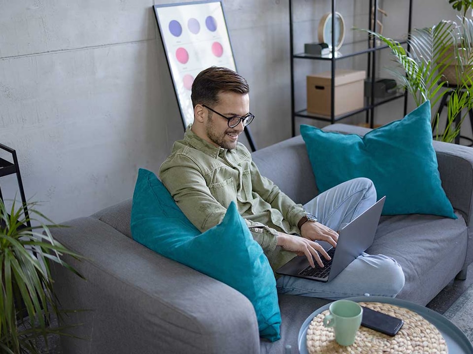 Mann sitter i sofa og setter opp budsjett